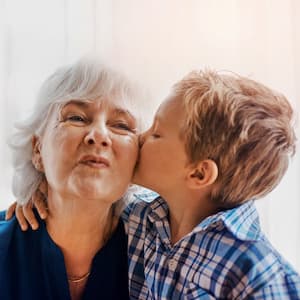 A young boy kissing his grandmother on the cheek as she smiles