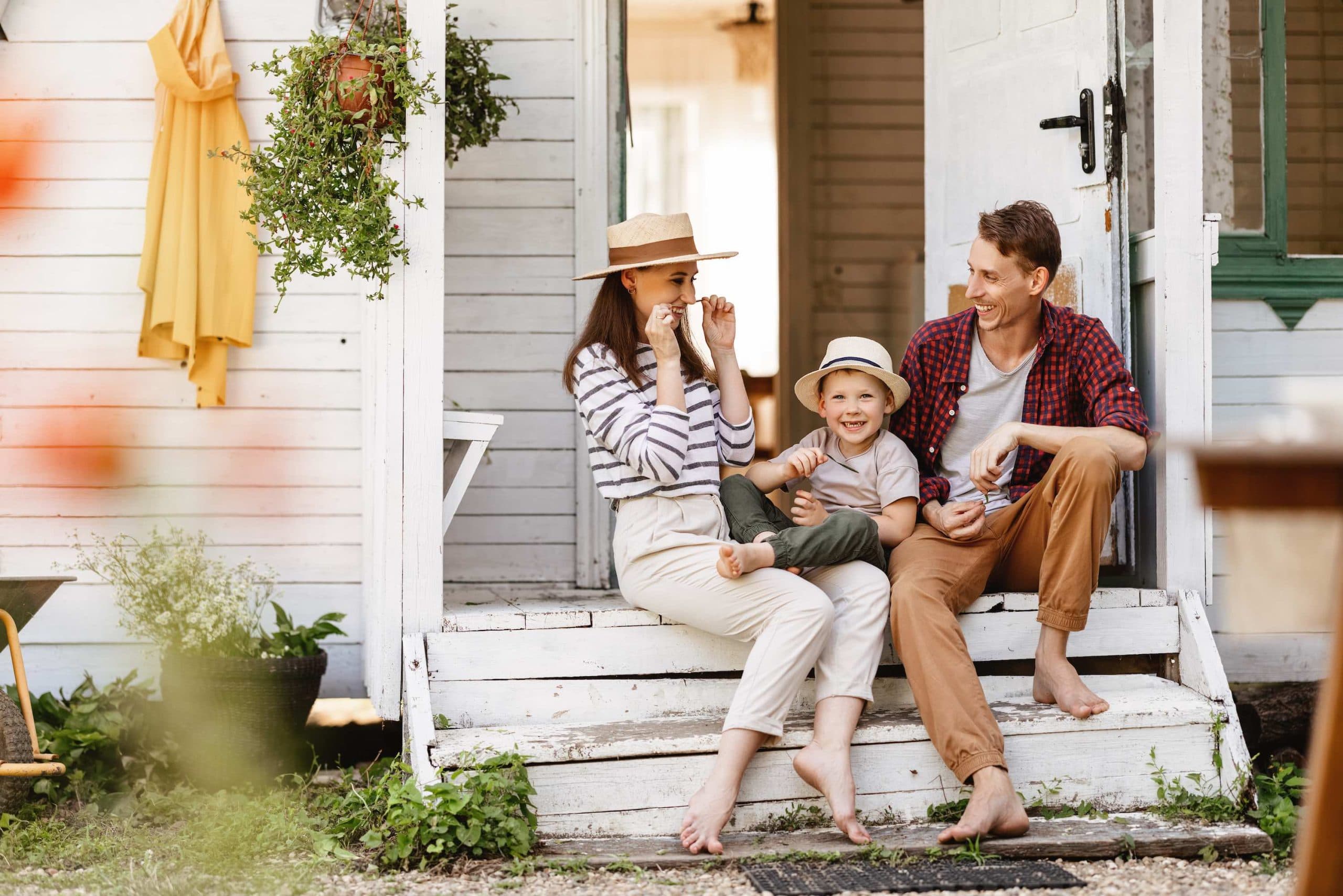 Parents and their children sitting together on the front steps of a porch