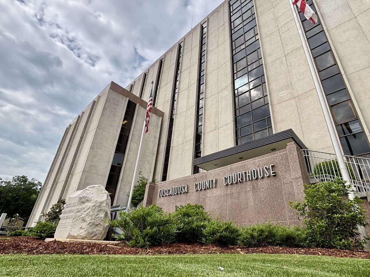 The Tuscaloosa County Courthouse on Greensboro Avenue, with its name on the granite wall by the entrance and flags flying above
